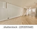 an empty living room with wood flooring and staircase leading up to the second floor in a white painted wall