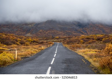 Empty long asphalt road leading to mountain and majestic fog, Beautiful scenic landscape in autumn season of Iceland