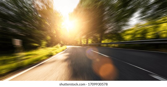 Empty long mountain road to the horizon on a sunny summer day at bright sunset with motion blur, Backplate or Backdrop background.
