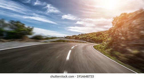 Пустая длинная горная дорога к горизонту в солнечный летний день на ярком закате - эффект размытия скорости движения