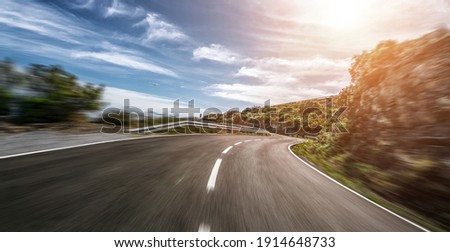Empty long mountain road to the horizon on a sunny summer day at bright sunset - speed motion blur effect