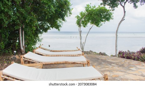 Empty Lounge Chairs On The Ocean Coast. Tourist Resort On Quarantine. Lounge Chair On Seascape Background. Tropical Resort Landscape With Low Tide. Outdoor Leisure Furniture. Recreation Concept. 