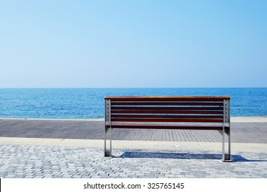 Empty low bench at the coast of the blue sea