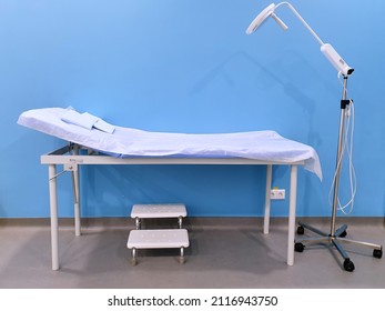 Empty medical bed on blue background, steps nearby, examination room. therapy. Modern medical technologies and medical equipment.