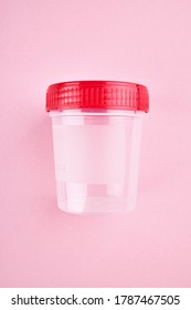 empty medical urine sample container over pink background. medical exam concept.