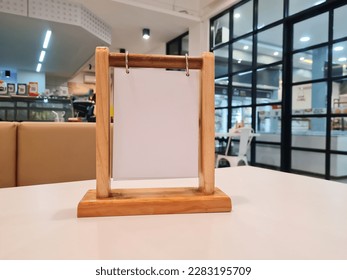 empty menu frame label board in Bar restaurant, Stand for booklet with marquee card acrylic white paper sheet on wooden table cafeteria blurred background can insert customer text.