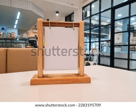 empty menu frame label board in Bar restaurant, Stand for booklet with marquee card acrylic white paper sheet on wooden table cafeteria blurred background can insert customer text.