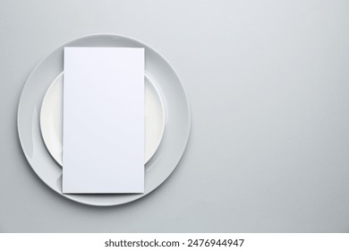 Empty menu and plates on light grey background, top view. Mockup for design