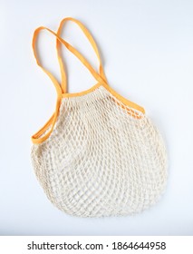 Empty Mesh Shopping Bag, White Net Cotton String With Yellow Holding Border On White Background. Tote Bag Contain Vegetable Or Fruit, Reuseable And Washable, Eco Market Bag Concept.
