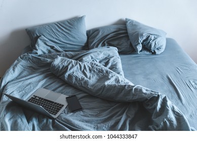 Empty Messy Grey Bed With Laptop. Lifestyle Rest In Bed Concept