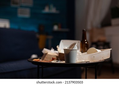 Empty messy living room with trash cans and leftovers rubbish on table, dirty space covered in garbage and unfinished snacks. Nobody in untidy unorganized and chaotic apartment.