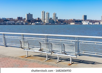 Empty Metal Bench At Pier I Along The Hudson River With A Clear Blue Sky In New York City	