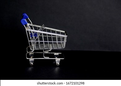 Empty metal market trolley is on the black background closeup taken with copy space around. Responsible consumption concept. Delivery food service concept