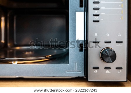 Empty microwave oven with open door. Closeup on buttons and knob on control panel for adjust mode and timer of microwave.