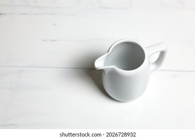 Empty Milk Jug On Wooden Background. Porcelain Sauce Boat, Pitcher, Creamer Or Ceramic Gravy Boat