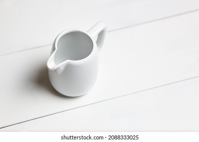 Empty Milk Jug On Wooden Background. Porcelain Sauce Boat, Pitcher, Creamer Or Ceramic Gravy Boat