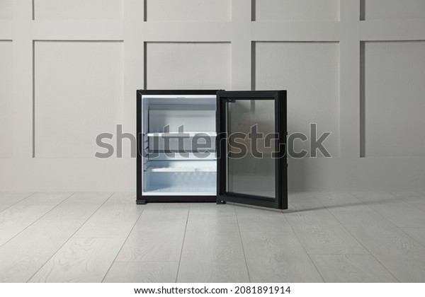 Empty mini bar with open glass door near beige\
wall indoors