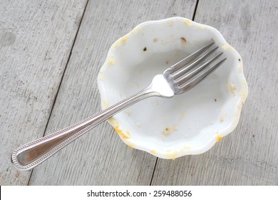 Empty Mini Casserole Dish With Fork On Rustic Wooden Background