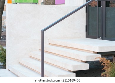 Empty minimalistic white stone stairway on the street. Metallic black handrail. Stylish. Design. Exterior. Handrails