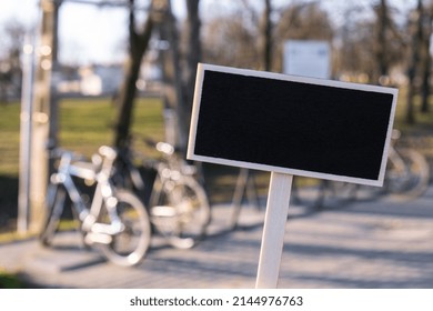 Empty mockup template Blackboard label against defocused background of bicycle sharing station. Bikes on the Bicycle parking. Bicycle rental in the big city. Eco-friendly modes of transport