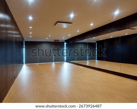 Empty modern dance studio interior with wooden floor, large wall mirror, spotlights, and blinds. Ideal for fitness, Pilates, yoga, dance practice, or interior design concepts. Exercise and Wellness.