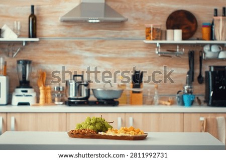 Empty modern kitchen with grapes on table. Open space kitchen room interior with daylight and blurred background. Design luxury arhitecture residential decoration.