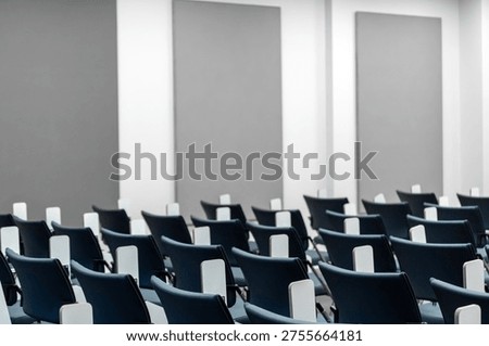 Empty modern lecture hall with rows of blue ergonomic chairs and folding desks, ideal background for education, corporate training, academic seminars, and professional workshop presentations.
