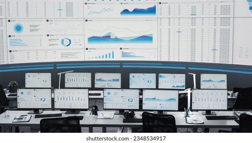 Empty Modern Monitoring Office With Big Digital Screen And Working Places of Employees With Desktop Computers and Monitors. Graphs And Charts Showing Financial Data And Reports Of Consulting Company.