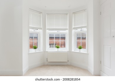 An empty modern room in an urban apartment with plain white walls and bay window in the UK