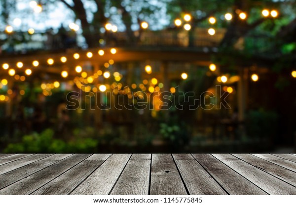 empty modern wooden
terrace with abstract night light bokeh of night festival in
garden, copy space for display of product or object presentation,
vintage color tone