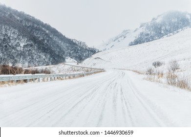 Empty mountain asphalt road in winter covered with snow on a cloudy day. The concept of driving a car in winter ice and travel - Powered by Shutterstock