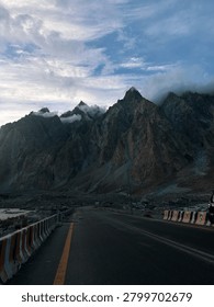 Empty Mountain Road Leading to Dramatic Snow-Capped Peaks and Dark cloud