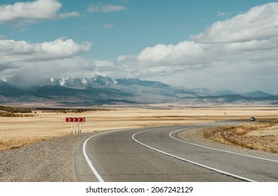 Empty Mountain Road With A Single Car And Sharp Turn Traffic Sign. Two Lane Highway Altay Region. Travel Layout