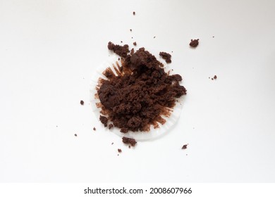 Empty Muffin Wrapper With Chocolate Muffin Crumbs. Top Down View Of Mess Against A White Background.