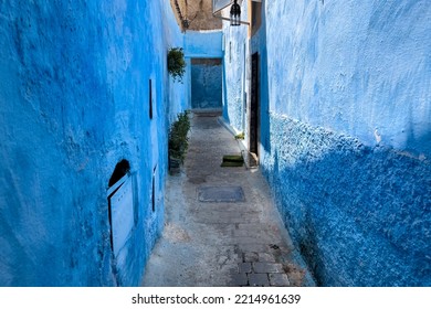 An empty narrow street with blue buildings in Chefchaouen - Powered by Shutterstock