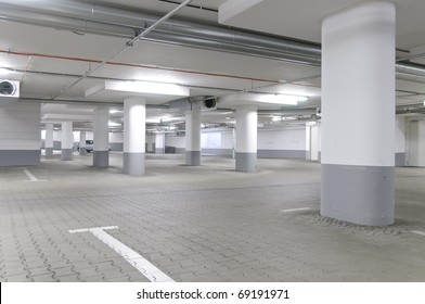 An empty, newly built underground car park in a gray concrete.