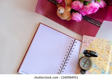empty note book with map, compass and a bouquet of flower on table for wishes and background
