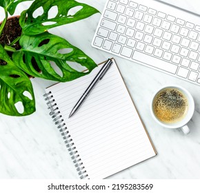 Empty Note Pad On Desk And Pen, With Keyboard,coffee And Green Plant. Top Down View, Copy Space..