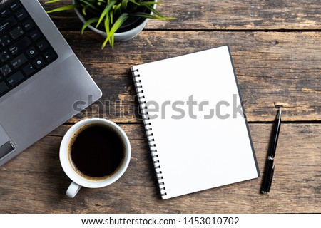 empty notebook with coffee and computer on wooden table ,top view