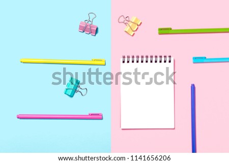 Empty Notebook or notepad on blue and pink background. Various pens. Creative minimalism chancery concept. Top view, flat lay.