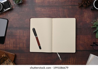 Empty notebook and pen on wooden background.