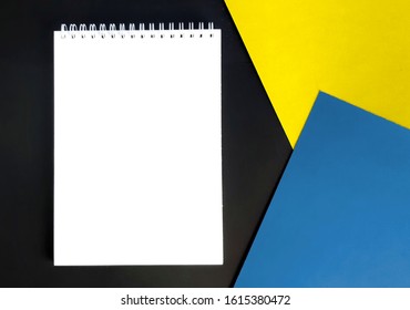 Empty notepad, bright yellow and blue paper blanks on blackboard. Mock up minimalist business composition. Banner for creative startup. Top view.