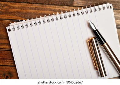 Empty notepad with fountain pen on wooden table