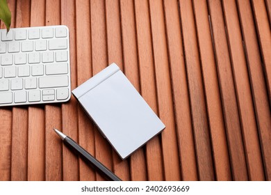 An empty notepad with pen, and computer keyboard on the wooden table. PTO concept. Copy space for text, message, information, etc.