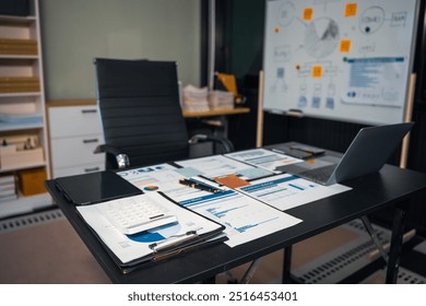 An empty office desk at night with a laptop displaying a business chart, balance sheet, loan calculator, graphs, and monthly budget stats. Blue and black tones, leather office chair. - Powered by Shutterstock