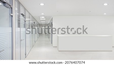 Empty office hall with glass walls and doors. Reception desk and corridor.