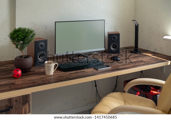 Empty office with large\
desktop computer monitor, speakers and bonsai on a wooden desk with\
mobile phone