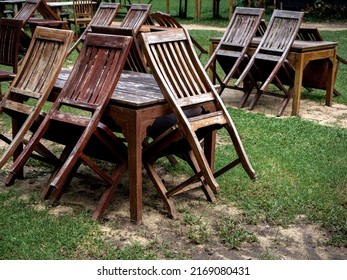 Empty Old Abandoned Wooden Dining Table Set On The Green Yard Garden. Outdoor Restaurant Permanently Closed With Old Dining Table No Use.