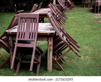 Empty Old Abandoned Wooden Dining Table Set On The Green Yard Garden. Outdoor Restaurant Permanently Closed With Old Dining Table No Use.