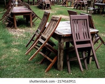 Empty Old Abandoned Wooden Dining Table Set On The Green Yard Garden. Outdoor Restaurant Permanently Closed With Old Dining Table No Use.